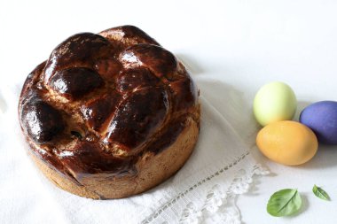 Geleneksel tatlı ekmek ve arka planda izole edilmiş renkli Paskalya yumurtaları. Paskalya tatili konsepti. Boşluğu kopyala.