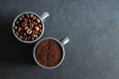 Gri arka planda iki kahve çekirdeği ve öğütülmüş kahve fincanı. Genel bakış. Boşluğu kopyala.