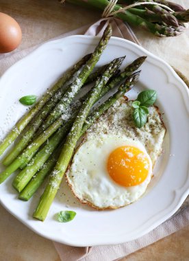 Yeşil kuşkonmaz ve üzerine parmesan serpiştirilmiş yumurta. Sağlıklı yiyecekler. Kahvaltı konsepti. Tam üstte.