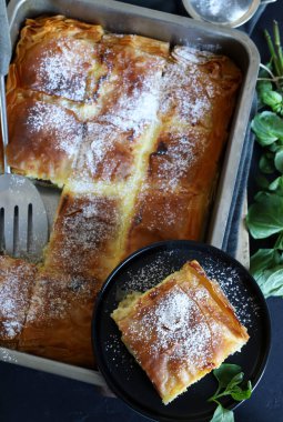 Yunan mutfağı. Ev yapımı geleneksel Yunan Bougatsa peynirle doldurulmuş ve üzerine pudra şekeri serpiştirilmiş fillo hamur işi. Tam üstte.