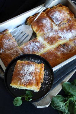 Yunan mutfağı. Ev yapımı geleneksel Yunan Bougatsa peynirle doldurulmuş ve üzerine pudra şekeri serpiştirilmiş fillo hamur işi. Tam üstte.