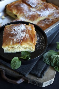 Yunan mutfağı. Ev yapımı geleneksel Yunan Bougatsa peynirle doldurulmuş ve üzerine pudra şekeri serpiştirilmiş fillo hamur işi. Tam üstte.