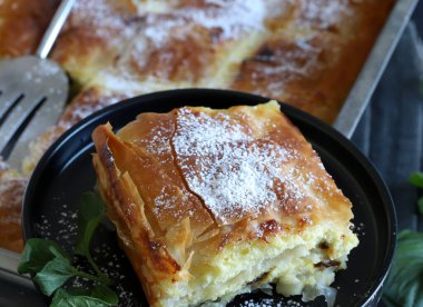 Yunan mutfağı. Ev yapımı geleneksel Yunan Bougatsa peynirle doldurulmuş ve üzerine pudra şekeri serpiştirilmiş fillo hamur işi. Tam üstte.