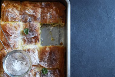 Yunan mutfağı. Ev yapımı geleneksel Yunan Bougatsa peynirle doldurulmuş ve üzerine pudra şekeri serpiştirilmiş fillo hamur işi. Tam üstte.