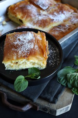 Yunan mutfağı. Ev yapımı geleneksel Yunan Bougatsa 'sı, peynirle doldurulmuş fillo hamur işi ve üzerine şeker serpiştirilmiş. Tam üstte.