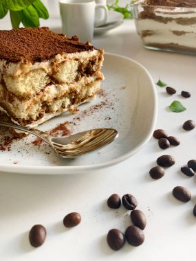 İtalyan kahvesi tiramisusu. Beyaz arka planda kadın parmaklı ve maskaralık kremalı klasik kahve tiramisusu. İtalyan tatlısı.