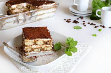 İtalyan kahvesi tiramisusu. Beyaz arka planda kadın parmaklı ve maskaralık kremalı klasik kahve tiramisusu. İtalyan tatlısı.