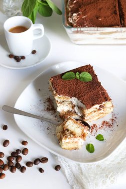 İtalyan kahvesi tiramisusu. Beyaz arka planda kadın parmaklı ve maskaralık kremalı klasik kahve tiramisusu. İtalyan tatlısı.