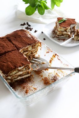 İtalyan kahvesi tiramisusu. Beyaz arka planda kadın parmaklı ve maskaralık kremalı klasik kahve tiramisusu. İtalyan tatlısı.