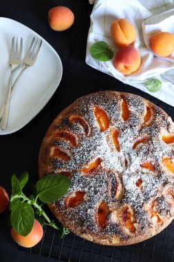 Siyah arka planda taze nane yapraklarıyla dekore edilmiş nefis ev yapımı kayısı pastası. Yaz tatlısı. Tam üstte.