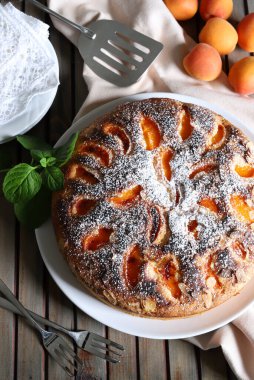 Ahşap arka planda izole edilmiş taze nane yapraklarıyla dekore edilmiş nefis ev yapımı kayısı pastası. Yaz tatlısı. Tam üstte.