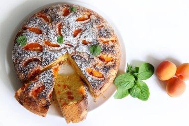 Beyaz arka planda izole edilmiş taze nane yapraklarıyla dekore edilmiş nefis ev yapımı kayısı pastası. Yaz tatlısı. Tam üstte.