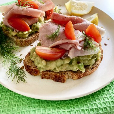 Fırında jambonlu avokado tostu (prosciutto) ve beyaz arka planda domates. Sağlıklı gıda konsepti. Genel Görünüm.
