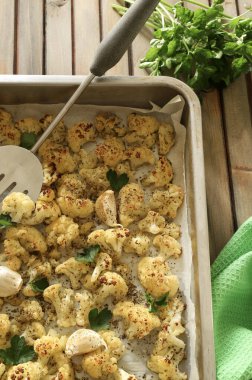 Ahşap masada fırında pişmiş karnabahar ızgaralı bir tepsi. Vejetaryen yemeği. Ev yapımı yemek konsepti. Tam üstte.