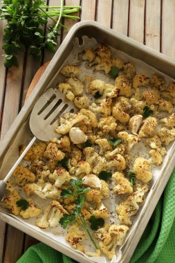 Ahşap masada fırında pişmiş karnabahar ızgaralı bir tepsi. Vejetaryen yemeği. Ev yapımı yemek konsepti. Tam üstte.