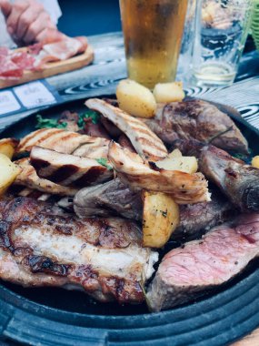 Pirzola, sosis, sığır eti, tavuk ve fırında patates ile nefis ızgara tabağı. Tam üstte.