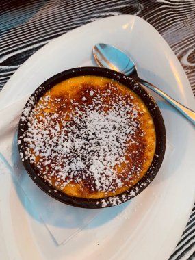 Crme brle beyaz tabakta servis ediliyor. Kaşık tatlısı. Tam üstte.