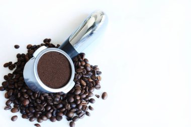 Filtre tutacağında öğütülmüş kahve ve beyaz arka planda izole edilmiş kahve çekirdekleri. Tam üstte. Boşluğu kopyala.