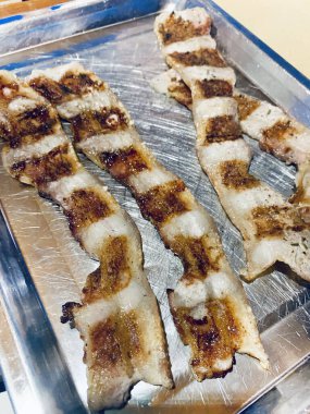 Izgarada kızartılmış ince dilimler halinde leziz ve çıtır pastırma, aperatif. Tam üstte.