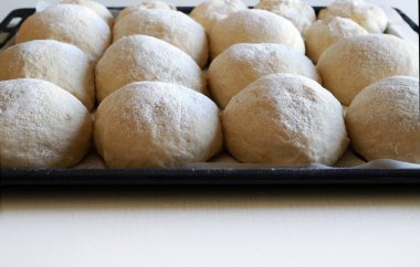 Fırın tepsisinde pişmemiş yuvarlak ekmek. Ev yapımı yemek konsepti. Tam üstte.