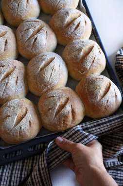 Ev yapımı taze çöreklerle birlikte bir yemek tepsisi tutarak. Tam üstte.