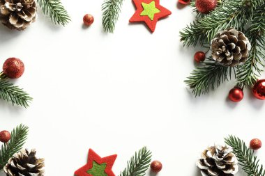 Yeni yıl kompozisyonu. Beyaz arka planda Noel arkaplanı. Dallar, kırmızı toplar, koniler. Tam üstte.