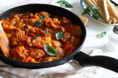 Ahşap masadaki tepside biberli ve domates soslu ev yapımı tavuk nuggetları. Tam üstte.