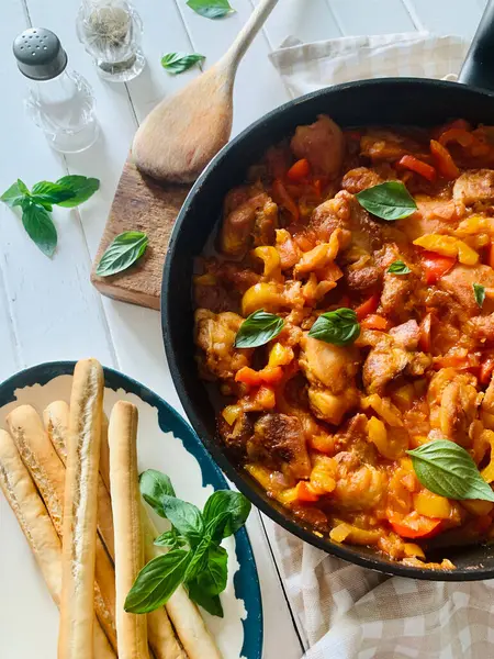 Ahşap masadaki tepside biberli ve domates soslu ev yapımı tavuk nuggetları. Tam üstte.