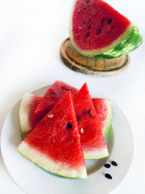 Beyaz ahşap arka planda yarım karpuz ve karpuz dilimleri. Sağlıklı yaz meyvesi.