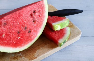 Gri ahşap arka planda yarım karpuz ve karpuz dilimleri. Sağlıklı yaz meyvesi. Yakın plan..