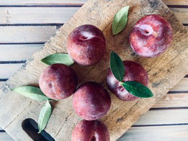 Ahşap arka planda izole edilmiş bir grup lezzetli erik meyvesi. Sağlıklı ve vejetaryen yemekleri. Tam üstte.