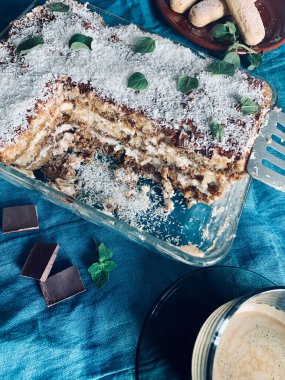 İtalyan Tiramisu 'su. Klasik kahve tiramisusu, hindistan cevizi, çikolata, kadın parmağı ve mavi arka planda mascarpone kreması. 
