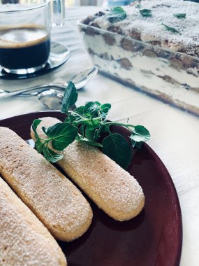 Tiramisu hazırlamak için bayan parmak bisküvileri, bulanık arka planda tiramisu ve kahve tepsisi. İtalyan tiramisu kavramı.