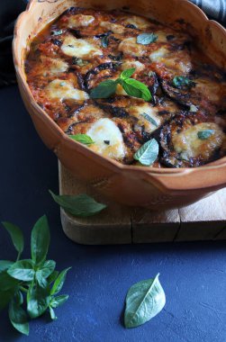 Fırında patlıcan parmigiana. Patlıcan, domates püresi, fesleğen, sarımsak ve peynir tabanlı bir tabak. Taze fesleğen yaprakları süsleme. İtalyan yemeği. Tam üstte.