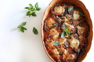 Baked aubergine parmigiana. Dish based on aubergines, tomato puree, basil, garlic and cheese. Fresh basil leaves decoration. Italian food. Directly above. clipart