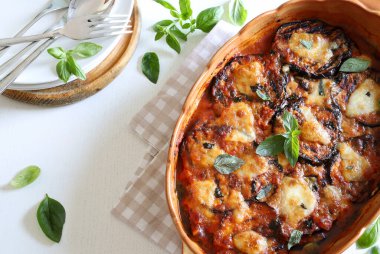 Fırında patlıcan parmigiana. Patlıcan, domates püresi, fesleğen, sarımsak ve peynir tabanlı bir tabak. Taze fesleğen yaprakları süsleme. İtalyan yemeği. Tam üstte.