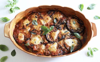 Fırında patlıcan parmigiana. Patlıcan, domates püresi, fesleğen, sarımsak ve peynir tabanlı bir tabak. Taze fesleğen yaprakları süsleme. İtalyan yemeği. Tam üstte.