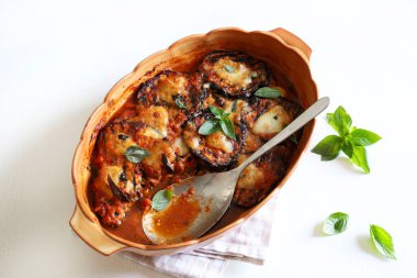 Fırında patlıcan parmigiana. Patlıcan, domates püresi, fesleğen, sarımsak ve peynir tabanlı bir tabak. Taze fesleğen yaprakları süsleme. İtalyan yemeği. Tam üstte.