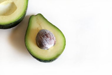 Avokado beyaz arka planda yarı izole bir şekilde ikiye bölündü. Sağlıklı ve vejetaryen yemekleri. Tam üstte.