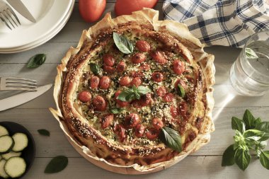 Kabaklı ev yapımı puf böreği, vişneli domates ve taze fesleğen yapraklarıyla süslenmiş. Sağlıklı ve vejetaryen yemekleri. Tam üstte.