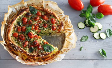 Kabaklı ev yapımı puf böreği, vişneli domates ve taze fesleğen yapraklarıyla süslenmiş. Sağlıklı ve vejetaryen yemekleri. Tam üstte.