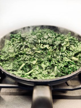 Siyah tavada sotelenmiş lahana ve mutfak sobasında zeytinyağı. Sağlıklı aşçılık kavramı. Ev yapımı doğal yemek. Vejetaryenler.