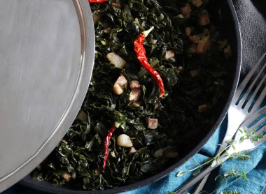 Siyah tavada sotelenmiş lahana, domuz pastırması küpleri, zeytinyağı ve kırmızı biber. Sağlıklı aşçılık kavramı. Ev yapımı doğal yiyecekler.. 