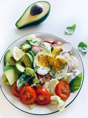 Beyaz ahşap masada yumurta ve avokado ile ev yapımı salata. Sağlıklı ve vejetaryen yemekleri. Tam üstte.