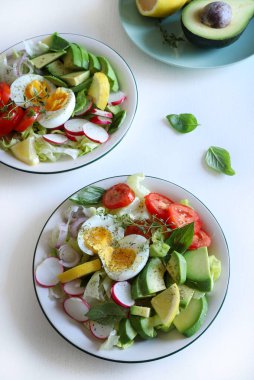 Beyaz ahşap masada yumurta ve avokado ile ev yapımı salata. Sağlıklı ve vejetaryen yemekleri. Tam üstte.