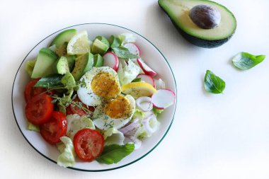 Beyaz ahşap masada yumurta ve avokado ile ev yapımı salata. Sağlıklı ve vejetaryen yemekleri. Tam üstte.