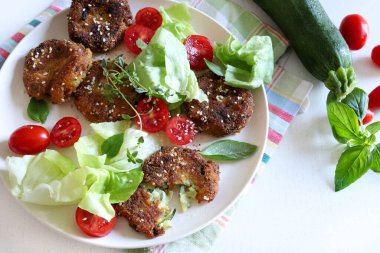 Ev yapımı vejetaryen kabak köftesi ve gri arka planda karışık sebze salatası. Sağlıklı ve vejetaryen yemekleri. Tam üstte.