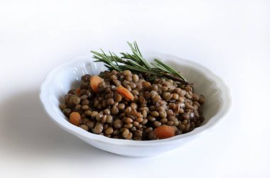 Beyaz bir masada, otlarla tatlandırılmış ev yapımı mercimek ve çiğ mercimek. Sağlıklı ve vejetaryen yemekleri. Tam üstte.