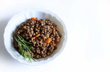 Beyaz bir masada, otlarla tatlandırılmış ev yapımı mercimek ve çiğ mercimek. Sağlıklı ve vejetaryen yemekleri. Tam üstte.