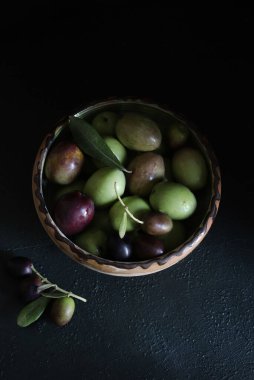 Arka planda bir kasede taze zeytin meyvesi. Vejetaryen ve sağlıklı yiyecekler. Tam üstte.